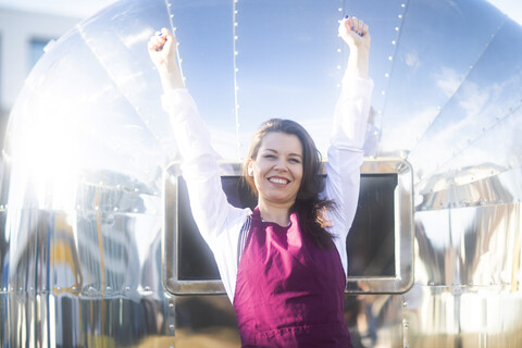 Porträt einer glücklichen jungen Frau an einem Imbisswagen mit Schürze, lizenzfreies Stockfoto