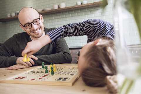 Vater und Tochter spielen ein Brettspiel in der Küche, lizenzfreies Stockfoto