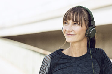 Sportliche Frau mit Kopfhörern, die ihr Fitnesstraining im Freien absolviert - MCF00085
