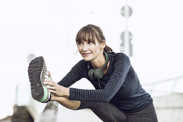 Sportive woman doing her fitness training outdoors, stretching - MCF00088