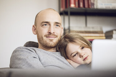 Vater und Tochter sitzen auf der Couch und benutzen einen Laptop - MCF00099