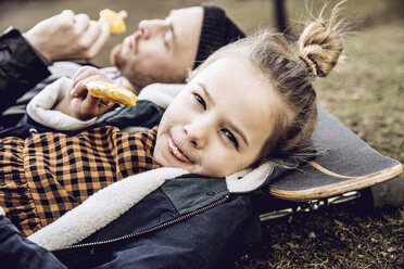 Vater und Tochter ruhen sich auf dem Skateboard aus und essen Eiscreme - MCF00106