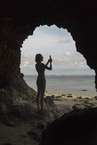 Junge Frau in einer Höhle, die ein Foto macht, lizenzfreies Stockfoto