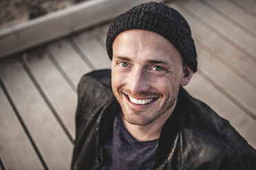 Portrait of smiling man with stubble wearing woolly hat - MCF00110