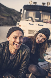 Portrait of lauging man with girlfriend and camper in the background - MCF00116