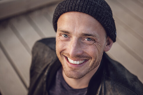 Portrait of smiling man with stubble wearing woolly hat - MCF00119