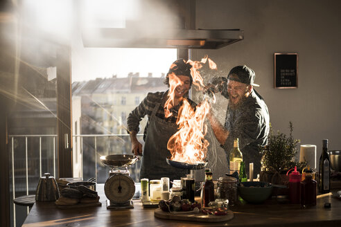 Freunde flambieren Essen in einer Pfanne, wodurch eine große Flamme entsteht - MJRF00027