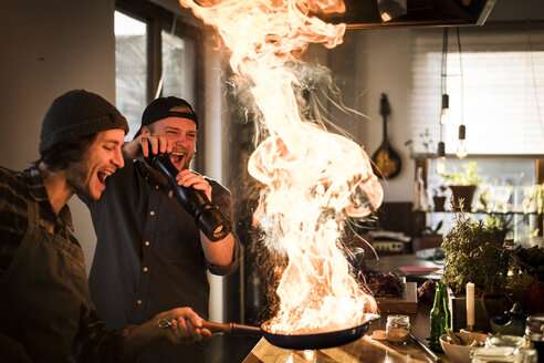 Freunde flambieren Essen in einer Pfanne, wodurch eine große Flamme entsteht - MJRF00060