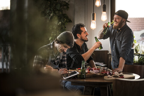 Freunde trinken Bier und essen gemeinsam, was sie gekocht haben, lizenzfreies Stockfoto
