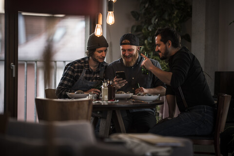 Freunde trinken Bier und essen gemeinsam, was sie gekocht haben, lizenzfreies Stockfoto