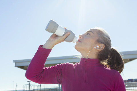 Sportive mature woman during workout, drinking stock photo