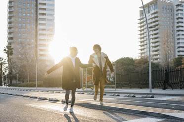 Glückliches Paar beim Laufen in der Stadt bei Sonnenuntergang - JRFF02705