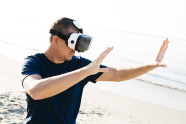 Man wearing VR glasses on the beach - HMEF00223