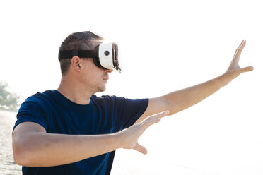 Man wearing VR glasses on the beach - HMEF00224