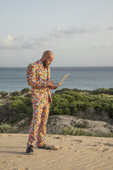 Man wearing suit with colourful polka-dots using laptop outdoors - KBF00522