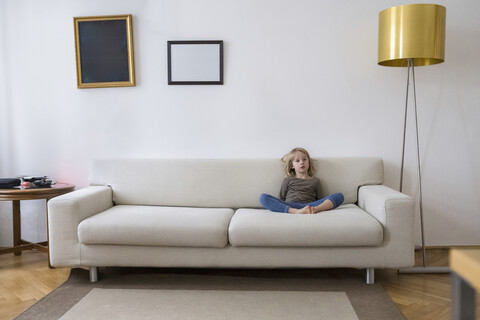 Bored girl sitting on the couch at home stock photo