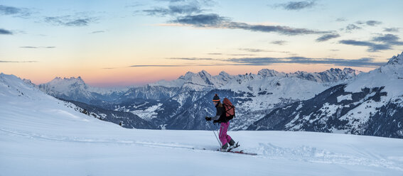 Schweiz, Bagnes, Cabane Marcel Brunet, Mont Rogneux, Frau beim Skitourengehen in den Bergen in der Abenddämmerung - ALRF01377