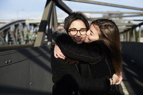 Glückliche Freunde umarmen sich auf einer Brücke, lizenzfreies Stockfoto