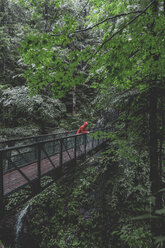 Deutschland, Bayern, Partnachschlucht bei Garmisch-Partenkirchen, Mann mit roter Regenjacke auf Brücke stehend, Regen - MMAF00831