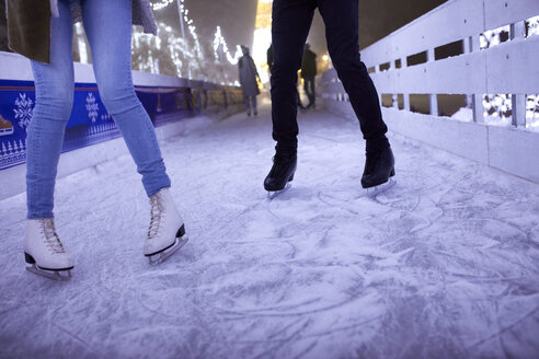 Beine eines Paares beim Schlittschuhlaufen auf einer nächtlichen Eislaufbahn - ZEDF01876