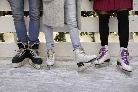 Beine von Freunden in Schlittschuhen auf einer Eisbahn, lizenzfreies Stockfoto