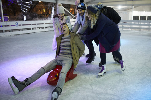 Glückliche, verspielte Freunde beim Schlittschuhlaufen auf einer Eislaufbahn - ZEDF01893