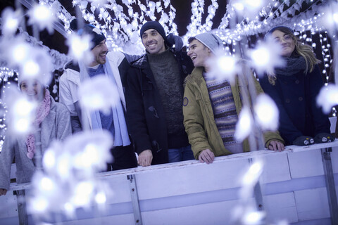 Glückliche Freunde stehen in festlicher Weihnachtsdekoration bei Nacht, lizenzfreies Stockfoto