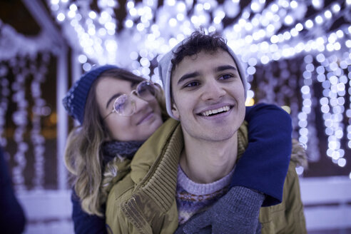 Glückliches junges Paar, das sich in der Winterdekoration umarmt - ZEDF01905