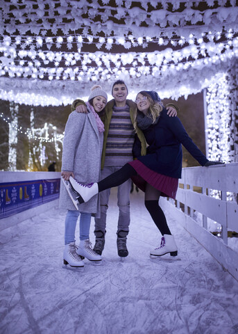 Glückliche Freunde auf einer nächtlichen Eislaufbahn, lizenzfreies Stockfoto