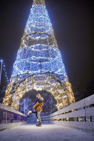 Happy young couple hugging on an illuminated festive ce rink at night stock photo