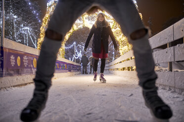 Junge Frau beim Schlittschuhlaufen auf einer nächtlichen Eislaufbahn - ZEDF01915