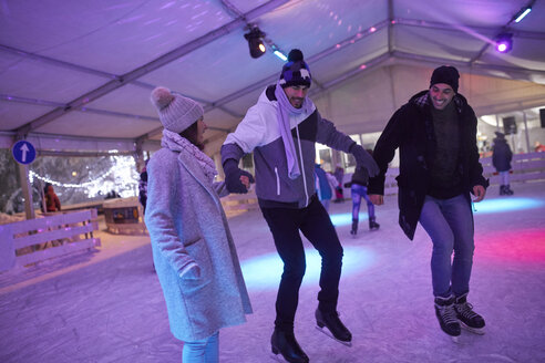 Glückliche Freunde beim Schlittschuhlaufen auf einer nächtlichen Eisbahn - ZEDF01922