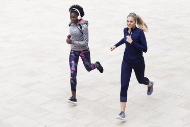 Zwei sportliche junge Frauen beim gemeinsamen Laufen in der Stadt - JSRF00118