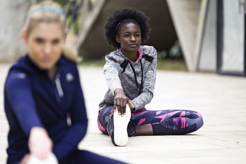 Zwei sportliche junge Frauen beim Stretching in der Stadt, lizenzfreies Stockfoto