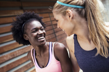 Zwei sportliche junge Frauen, die sich nach einem Lauf in der Stadt unterhalten und entspannen - JSRF00134