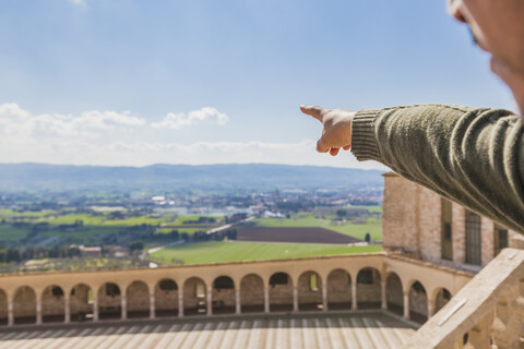 Italien, Umbrien, Assisi, männliche Hand, die auf die Felder um die Basilika San Francesco d'Assisi zeigt, lizenzfreies Stockfoto