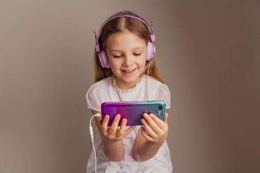 Portrait of smiling girl watching movie with smartphone and headphones - NMS00296