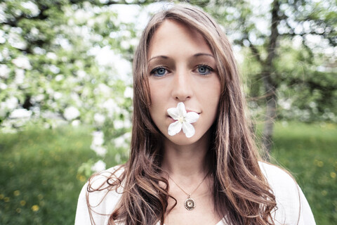 Porträt einer jungen Frau mit Apfelblüte im Mund, lizenzfreies Stockfoto
