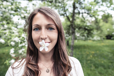 Porträt einer lächelnden jungen Frau mit Apfelblüte im Mund - WFF00023