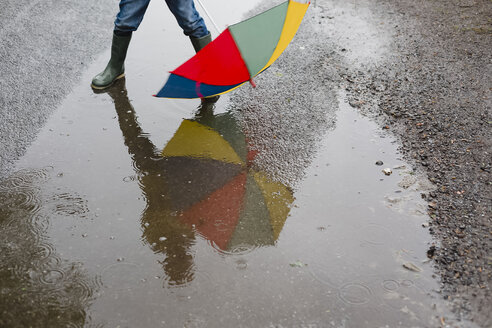 Little boy with umbrella and rubber boots standing in a puddle, partial view - NMS00300