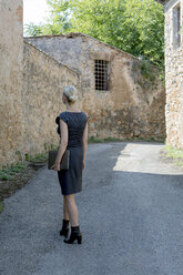 Italien, Toskana, Monteriggioni, Frau mit Laptop beim Spaziergang im Dorf - PSTF00295