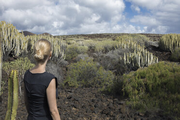 Spanien, Teneriffa, Malpais de Guimar, Frau in vulkanischer Landschaft mit Kakteen - PSTF00307