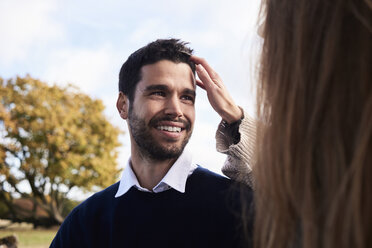 Happy man smiling at girlfriend in a park - IGGF00817