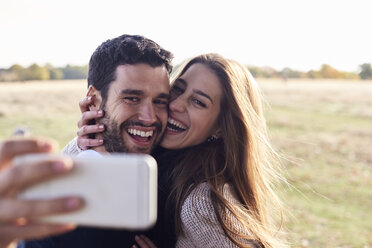 Ein glückliches Paar macht ein Selfie in einem Park - IGGF00827