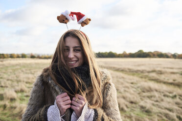 Porträt einer fröhlichen jungen Frau mit weihnachtlichem Kopfschmuck auf dem Lande - IGGF00828