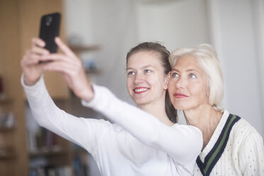 Porträt einer lächelnden jungen Frau, die ein Selfie mit ihrer Mutter macht - SGF02308