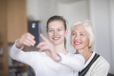 Porträt einer lächelnden jungen Frau, die ein Selfie mit ihrer Mutter macht - SGF02309