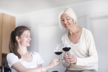 Mutter und Tochter im Rollstuhl bei einem Glas Rotwein zu Hause - SGF02338