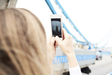 UK, London, woman taking photo with smartphone of Tower Bridge - IGGF00844