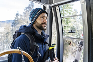 Germany, Bavaria, Brauneck, smiling man in winter in gondola lift - DIGF05902